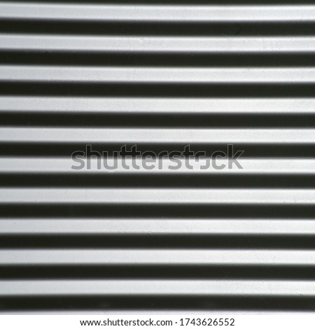 Fabricated corrugated steel reflects light, looks like steel bars that pop off the screen, machined grain dryer background abstract wallpaper negative copy space vivid eye-catching. Could turn 90 deg.