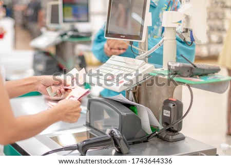 Female employee hand with cash counting money and hand receiving cash, paying checkout at cashier access in supermarket. Royalty-Free Stock Photo #1743644336