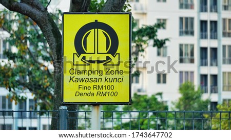 
Wheel clamping warning sign - no parking car
Malay word "Kawasan Kunci" Means that Clamping zone,
"Denda" Malay word means that Fine