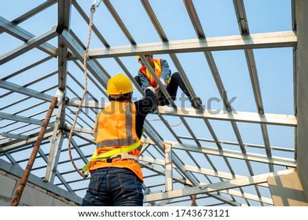 Builder Working On Roof Of New house,Concept of residential building under construction. Royalty-Free Stock Photo #1743673121