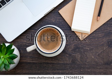 Wooden desk table with computer, notebook, pencil and hot coffee. Top view