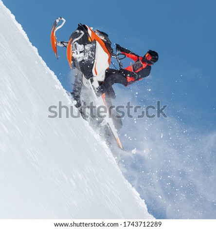 the guy is flying and jumping on a snowmobile on a background of blue sky leaving a trail of splashes of white snow. bright snowmobile and suit without brands. extra high quality  Royalty-Free Stock Photo #1743712289