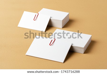 Pile of white businesscards with a clip on beige background