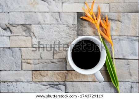 hot black coffee cup and flowers with  brick background