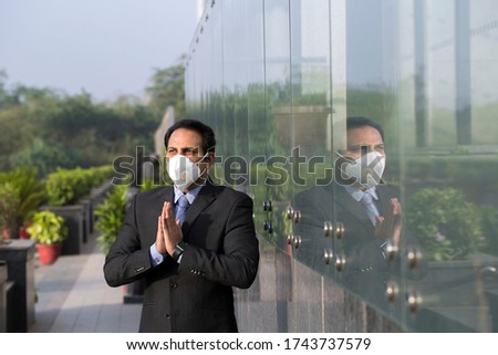 Businessman wearing face mask and greeting with namaste to prevent spread of virus 