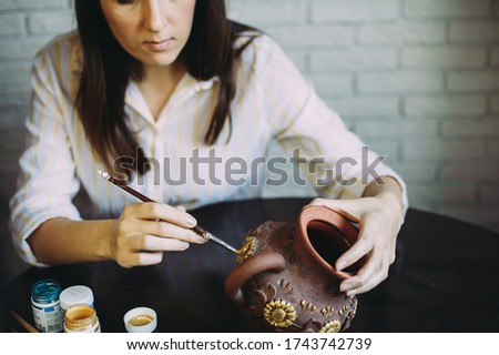 Girl artist paints a clay teapot in her studio. Creativity. Handwork. Art. Self employment