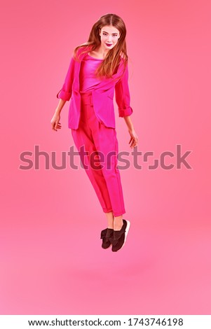 Beautiful fashion model posing at studio in trendy crimson suit on a pink background. Glamorous pink style. Full length portrait. 
