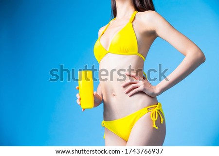 asian bikini girl take sunscreen with blue background