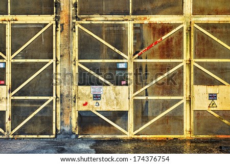 Yellow metallic door with high voltage warning signs in an abandoned factory