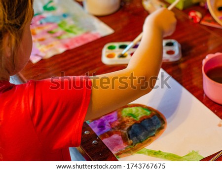 Child, Preschool girl drawing watercolors with bright paints on paper, closeup. home schooling for children.