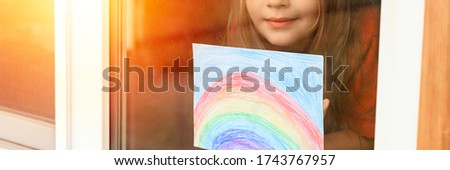 noisy effect. kid girl seven year old with drawing rainbow looks through the window during covid-19 quarantine. stay at home, let's all be well. flare. banner