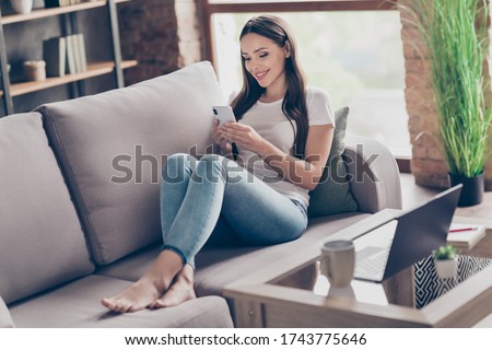 Photo of beautiful lady hold telephone hands browsing website resting work notebook table quarantine social distancing stay home sit cozy sofa divan living room indoors