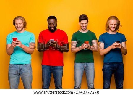 Photo of four people men youth use smartphone read social media news repost share comment feedback wear t-shirt denim jeans isolated over bright shine color background