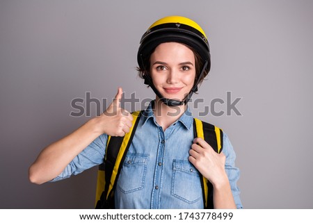 Portrait of confident successful girl courier get excellent delivery service show thumb up symbol carry thermal backpack wear helmet denim jeans shirt isolated over gray color background