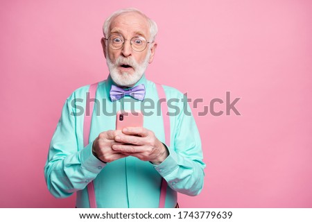 Photo of shocked stylish grandpa hold telephone hands read comments freelancer amazed wear specs mint shirt suspenders violet bow tie pants isolated pink pastel color background