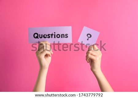 Woman holding sheets of paper with word QUESTIONS and query mark on pink background, closeup Royalty-Free Stock Photo #1743779792