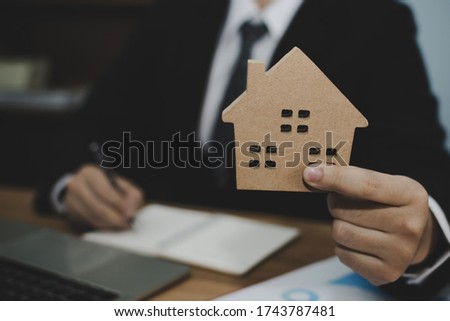 real estate broker manager in suit giving house model to customer after signing contract for buying house in estate agent office, real estate, finance, home loan contract, buy and sell house concept