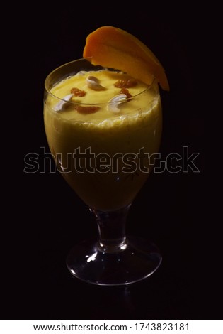 Refreshing Indian Mango Lassi (yogurt based) isolated in dark background
