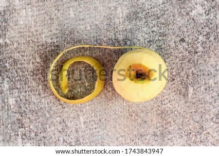 One peeled illuminating yellow apple on ultimate gray concrete background with light and shadow. Concept of spring, gardening, harvest, healthy food. Copy space. Color of the year 2021.