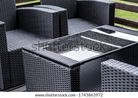 Close up view of wet synthetic plastic rattan and glass garden furniture. Garden furniture maintenance concept. Royalty-Free Stock Photo #1743863972