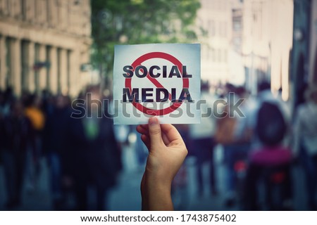 Social media censorship, political war between US president banning social networks. Hand holding a banner with forbidden sign over a crowded street background. Internet communication risk concept. Royalty-Free Stock Photo #1743875402