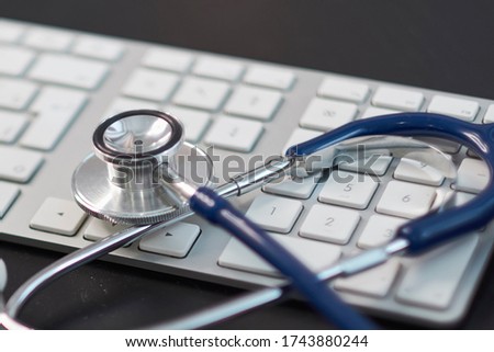 Silver stethoscope lying down on white keyboard, on black background. stock image photo. remote diagnostics