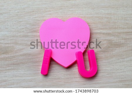 Letters I and U with a blank symbolic heart shaped sticker. Short Message I love you. Background