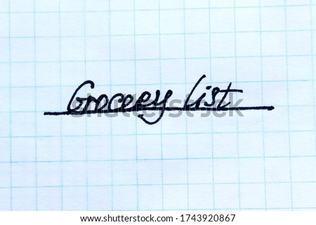 Close-up of a message Grocery List handwritten on a graph paper.