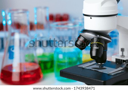 Scientific laboratory with microscope and test tubes with samples, close up photo