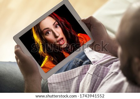 Human hands with tablet computer watching an online video with girl photo on the screen