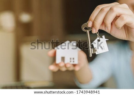Woman holding white house model and house key in hand.Mortgage loan approval home loan and insurance concept. Royalty-Free Stock Photo #1743948941