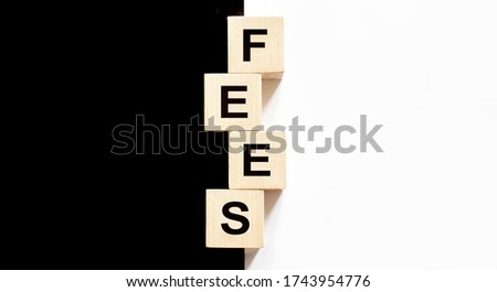 Business concept text Fees on wood block on the black and white background