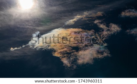 Iridescent clouds with sun on dark sky