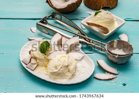 Lactose free coconut ice cream. Special spoon, halves of fruit, flakes. Vegan dessert concept. Trendy turquoise wooden boards background