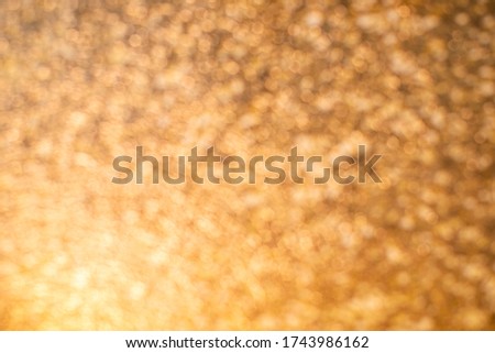An orange ray of light flickers across a golden, shiny blurry background. The texture glows and shines, an empty place for text and advertising, a glare of the sun, reflection on the smooth surface