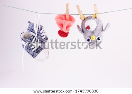 Pretty baby scene with handmade knitted toy. Crochet Amigurumi penguin toy, child sneakers hang dry on clothesline on white background.World crochet day concept.for children's social network pages  Royalty-Free Stock Photo #1743990830