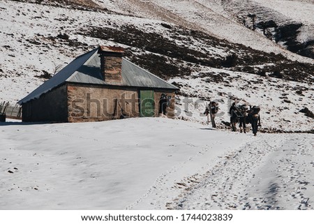 A group of hikers near the old building on the mountain covered with snow