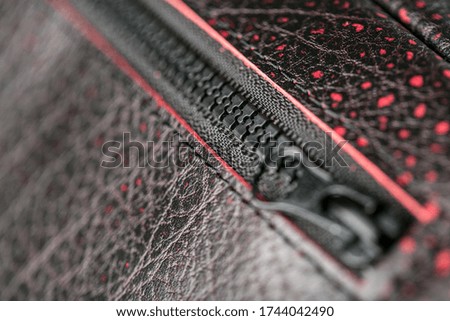 Zipper slider for a bag made of textured red leather.