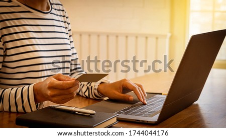 Young women hold credit cards and use laptops Online shopping and orange light