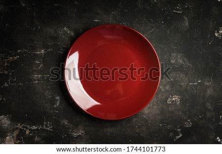 Clean red plate on the rustic background. Selective focus. Shot from above.
