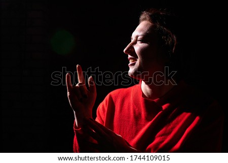 Portrait of middle age woman in red sweater on black background. Female model posing in studio in dark place