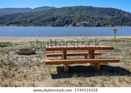 View of a picnic table and fire pit near the water at Lake Hemet, in California.