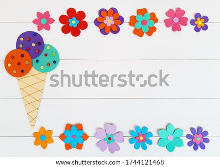 Composition of summer flowers, ice cream horn of multi-colored paper and sequins. Child make crafts his own hands. Cute DIY handmade art creativity on a white wooden table. Top view, copy space