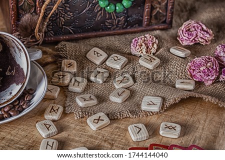 Esoteric concept of divination and prediction. Tarot cards, runes, coffee grounds in a cup, rosary, dried flower on a table against the background of an old chest. Royalty-Free Stock Photo #1744144040