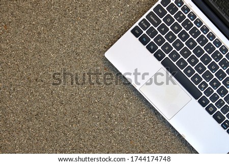 Flat lay photo of a modern laptop keyboard with a pebble-patterned background. Empty side for text.