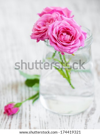 Glass with Bouquet of Roses on a wooden background