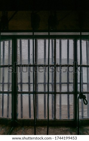 Window with railings, with sea in a rainy day in the background. Concept: closed place interior