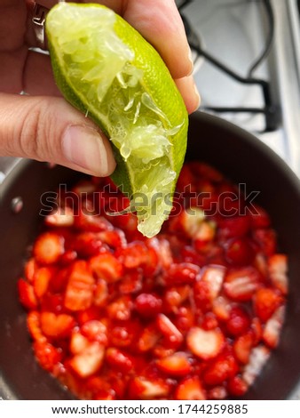 Adding lemon to make a strawberry jam. Boil strawberries in the pan. Texture fruit, recipe of strawberry jelly. Do it yourself process, homemade food. 