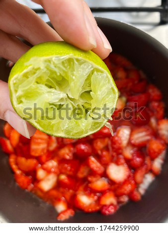 Adding lemon to make a strawberry jam. Boil strawberries in the pan. Texture fruit, recipe of strawberry jelly. Do it yourself process, homemade food. 