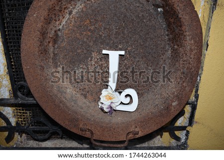 FLOWER DECORATED LETTERS ON AN OLD BURNER PLACED ON A WINDOW GRILLE